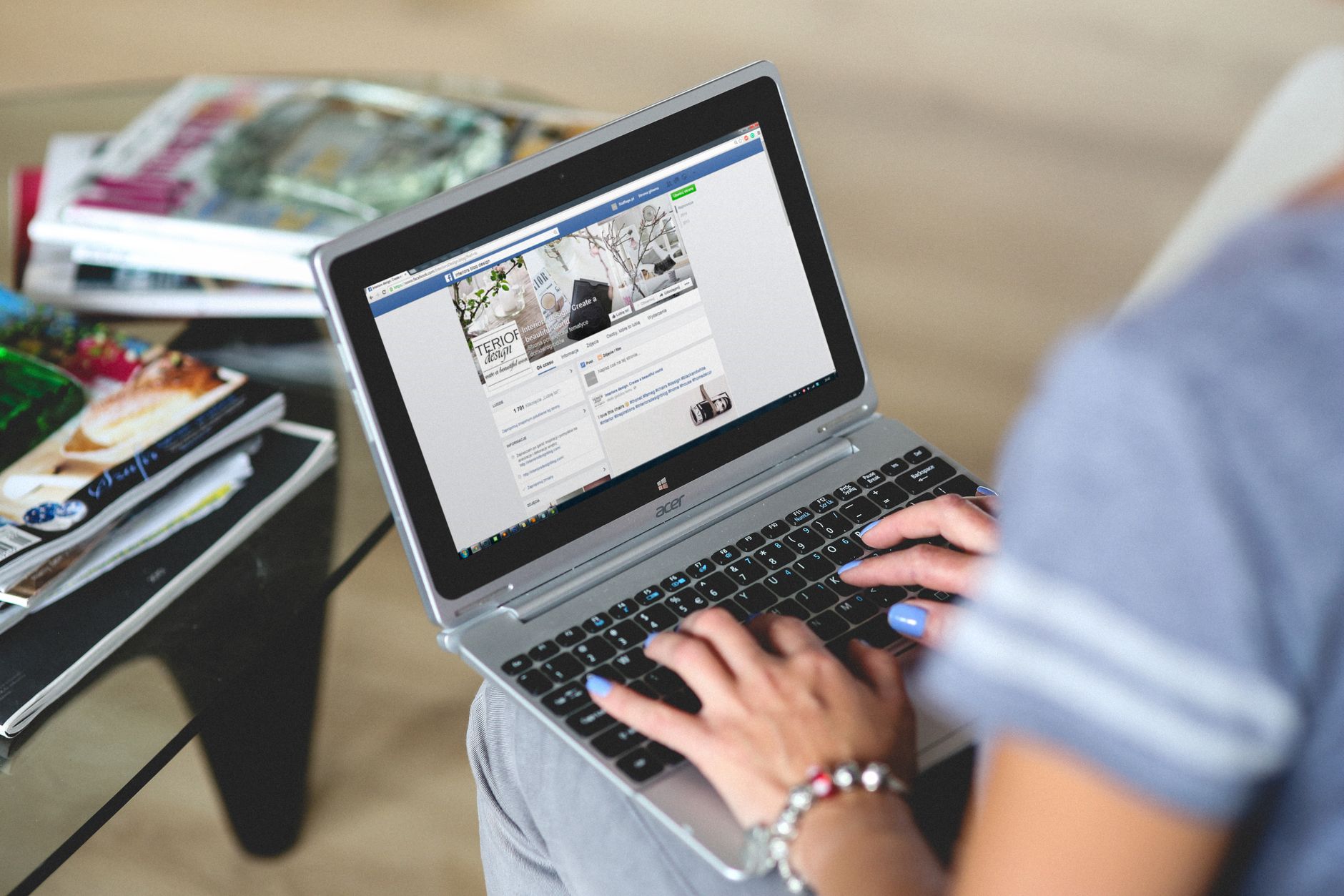 Les mains d’une personne qui tape sur un ordinateur portable ouvert sur une page web, posé sur ses genoux